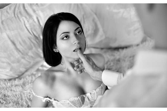 Man with his thumb on the lip of a woman kneeling in front of him