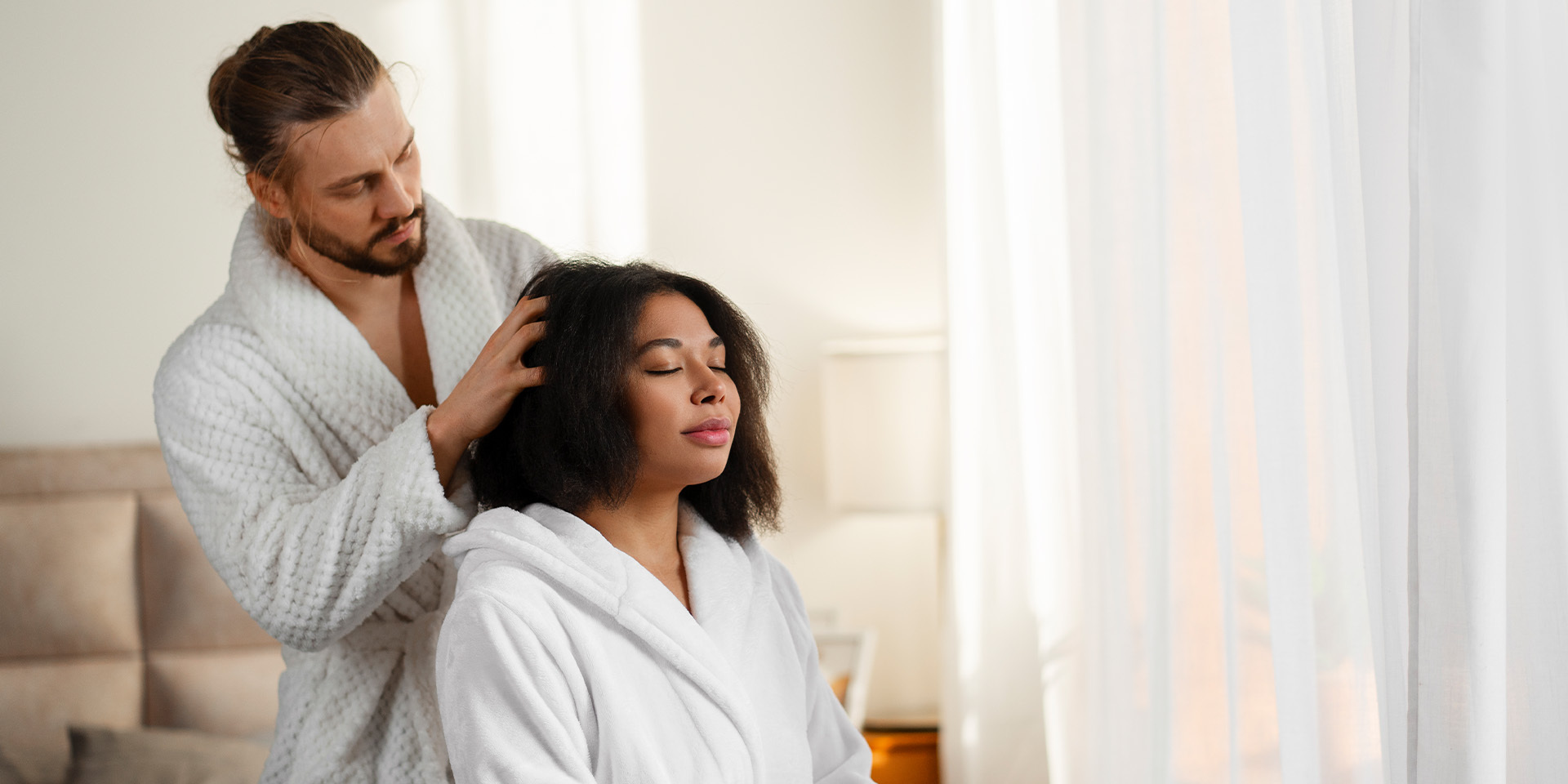 Man in bathrobe massaging his girlfriend's head