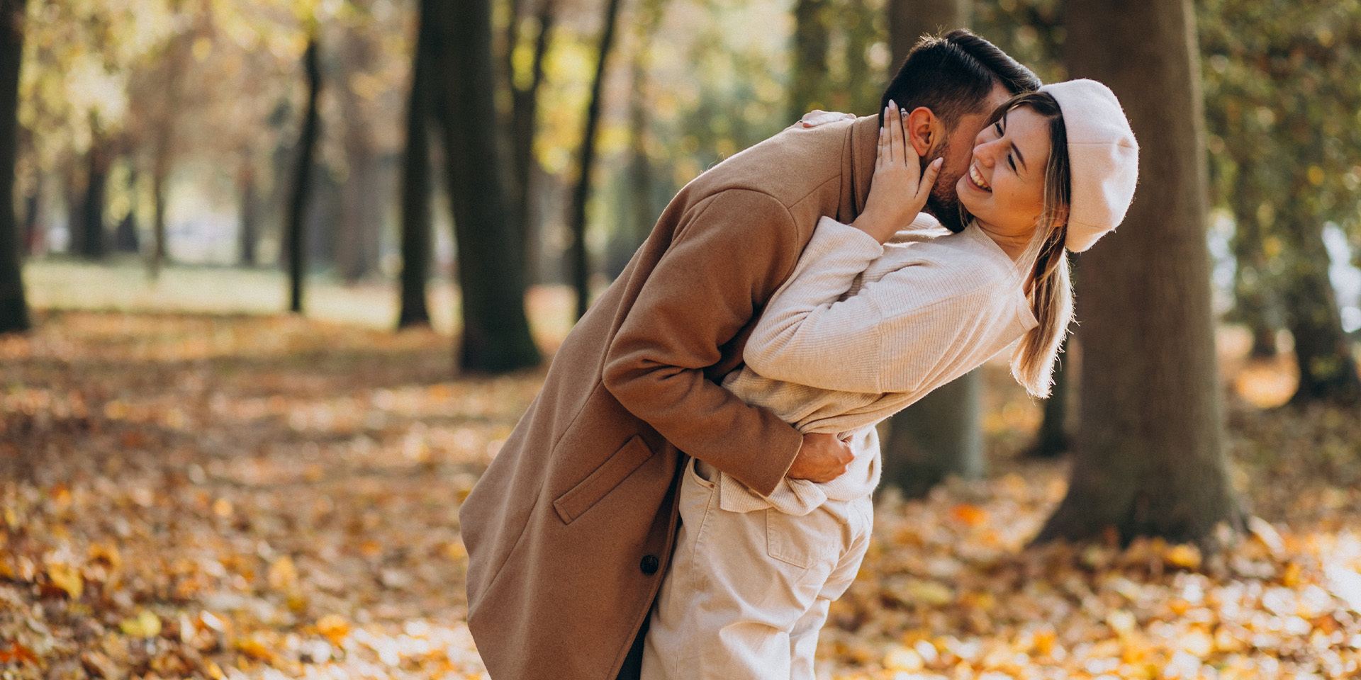 Couple embracing on an autumn walk in the woods with fallen leaves on the ground