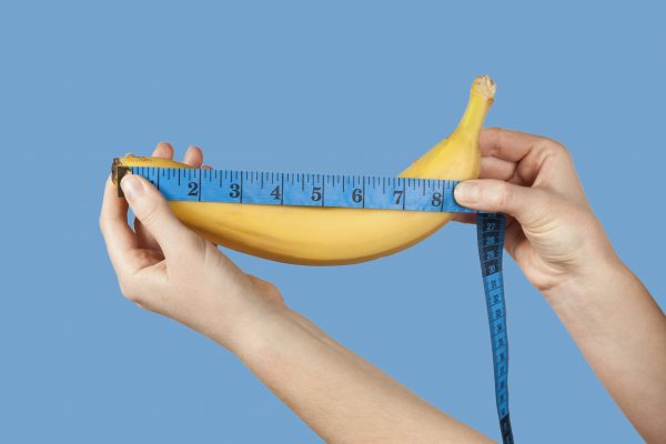 person measuring a banana