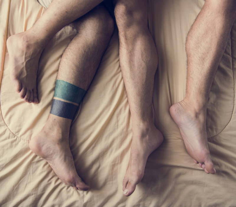Picture of the legs of two trans men being intimate in bed